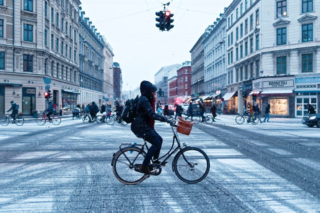 consigli per pedalare in inverno - ciclista in strada inverno pedala attraversando l'incrocio mentre nevica